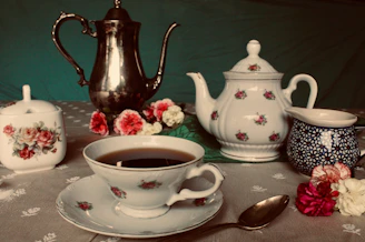 A vintage miniature tea set arranged on a tiny lace tablecloth.