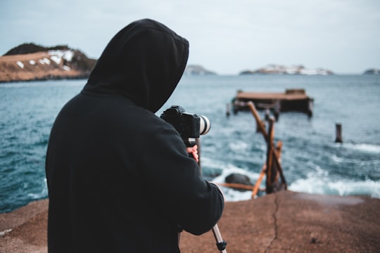 person in black hoodie holding black dslr camera in Tors Cove Canada