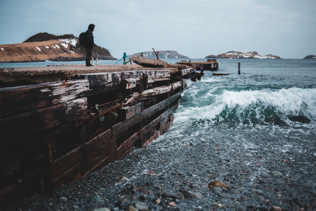 man in black jacket standing on brown wooden dock during daytime