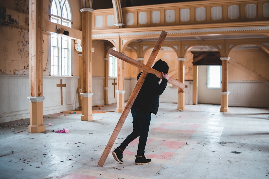 man in black jacket and black pants holding brown wooden stick