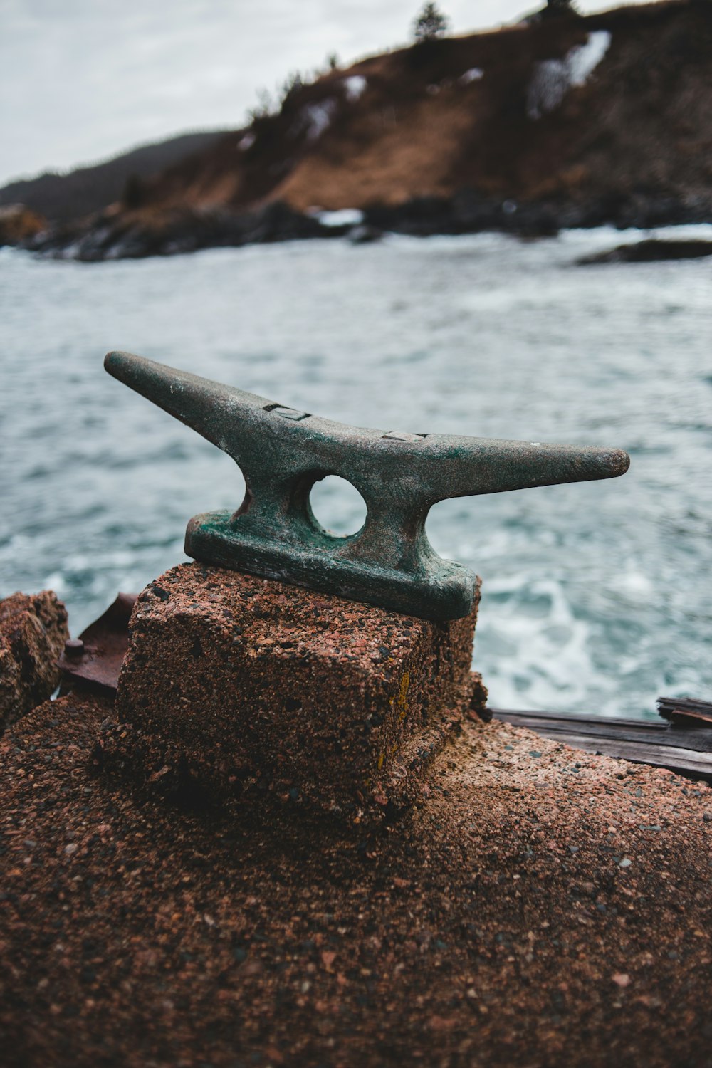 brown metal anchor on brown rock near sea during daytime