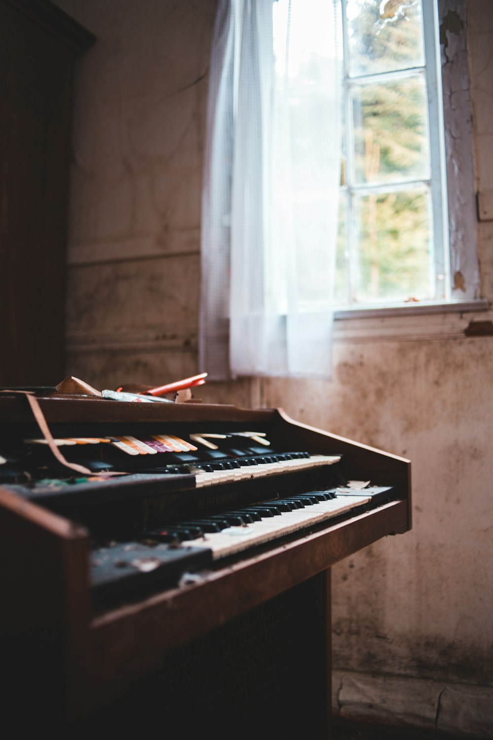 brown upright piano near window