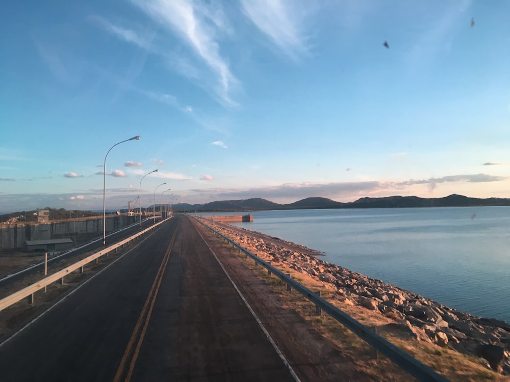 gray concrete road near body of water during daytime