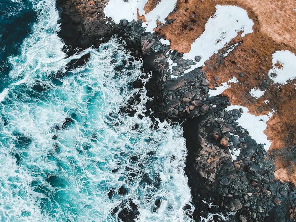 aerial view of ocean waves crashing on rocky shore during daytime