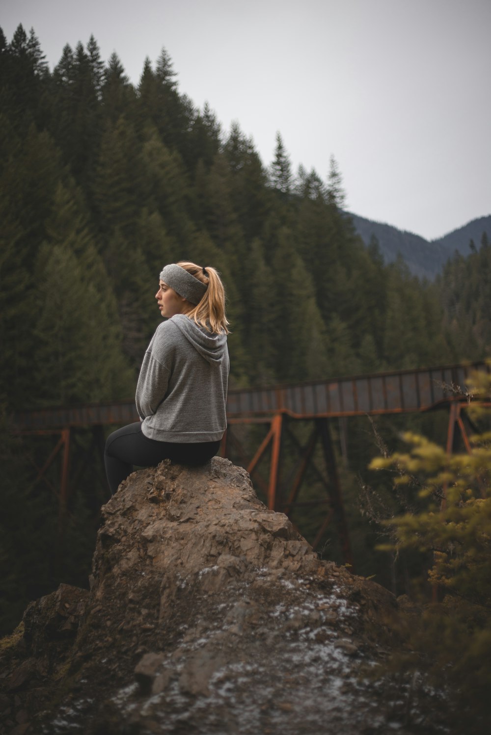 woman in gray hoodie sitting on brown rock during daytime