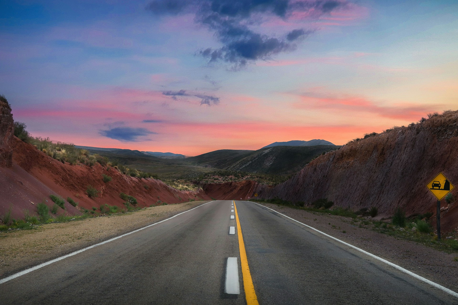 gray concrete road between brown mountains during daytime