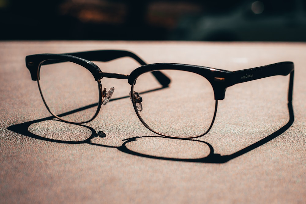 black framed eyeglasses on brown sand during daytime