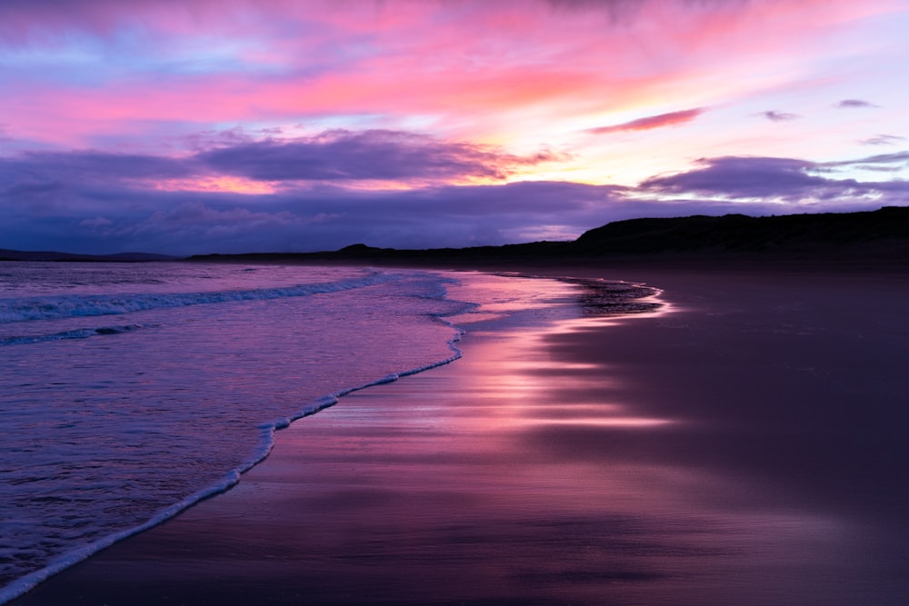 ocean waves crashing on shore during sunset