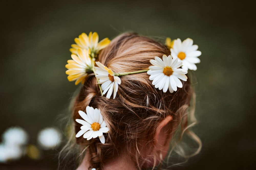 그녀의 머리에 흰색과 노란색 꽃을 가진 소녀