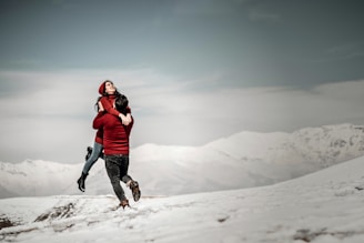 A vibrant winter scene showing a couple in matching ski outfits ready to hit the snowy slopes with skis and poles.