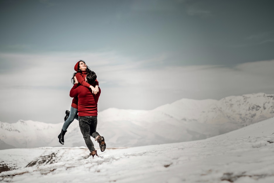 A vibrant winter scene showing a couple in matching ski outfits ready to hit the snowy slopes with skis and poles.