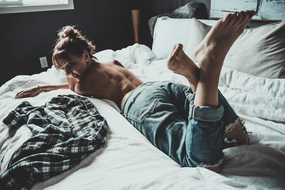 a shirtless young man laying on a bed