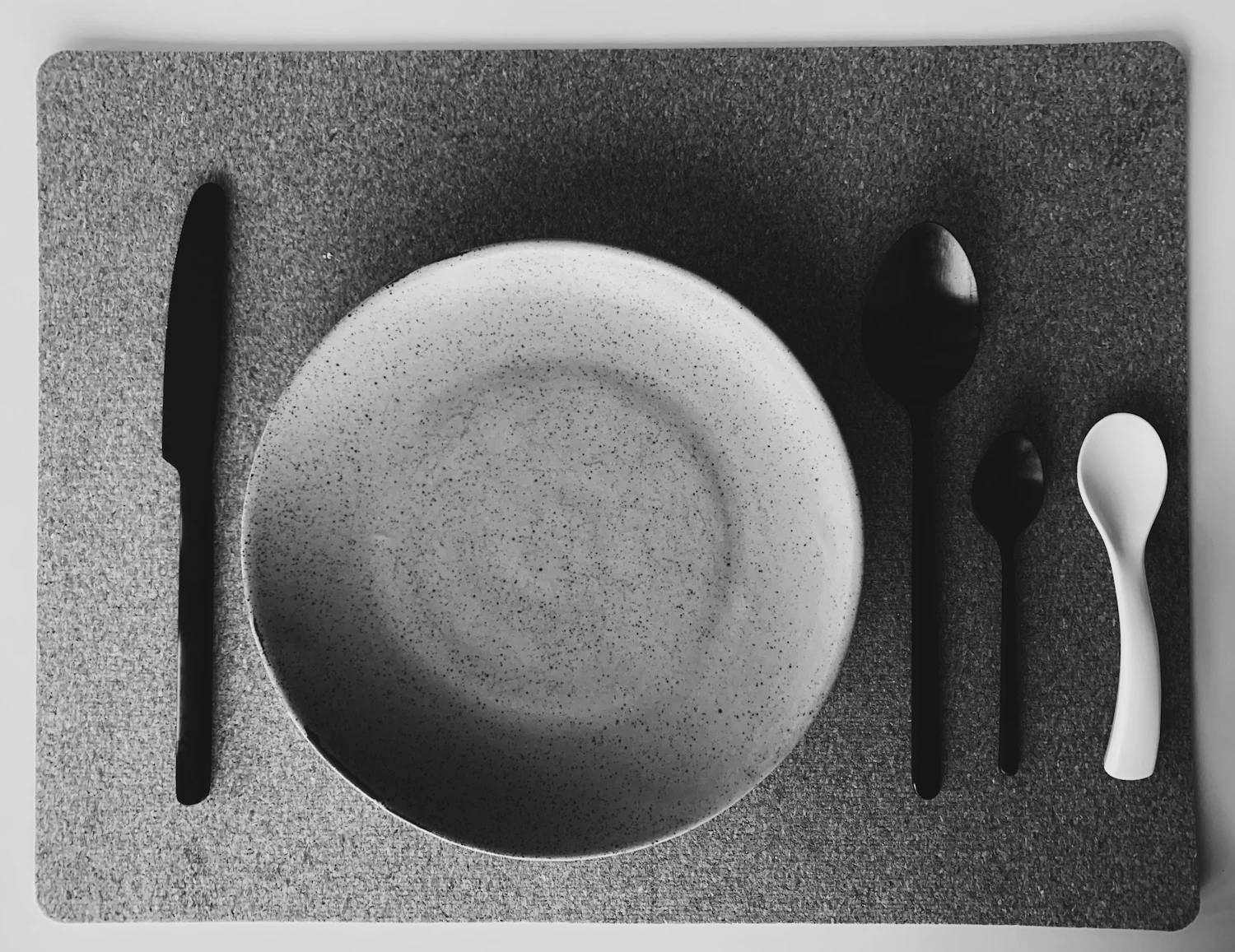 An empty plate with a knife, fork and spoon laid beside it, photographed from above