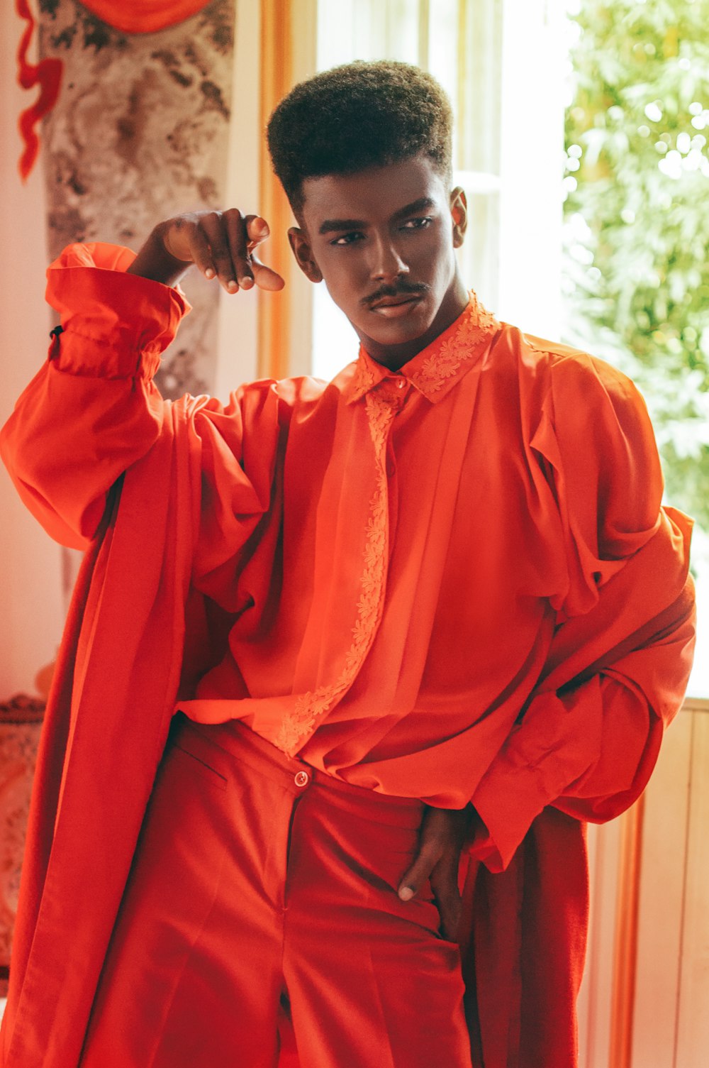 man in orange thobe standing near green trees during daytime