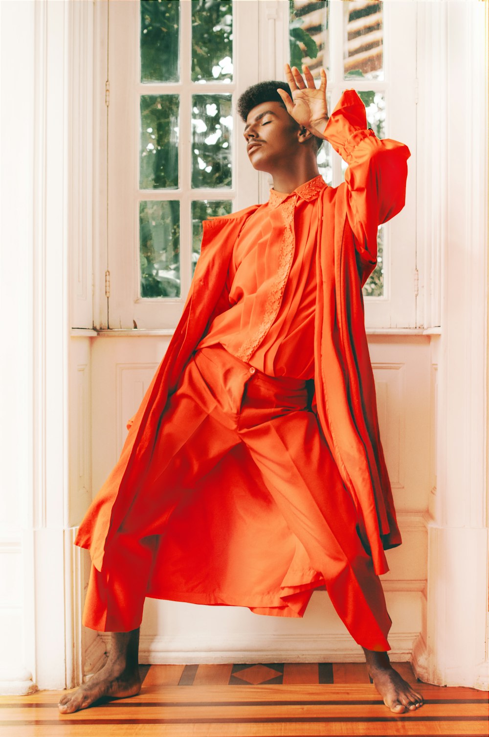 woman in orange long sleeve dress standing near window