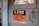 A worn, metal sign mounted on a wooden surface reads, 'A FIRE IN THIS BUILDING MIGHT PUT EVERY EMPLOYEE OUT OF WORK. Guard the Property Against Fire and Protect Your Job.' The sign features a bold black and red color scheme with a rustic backdrop.