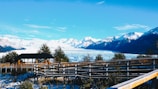 brown wooden fence on green grass field near snow covered mountain during daytime