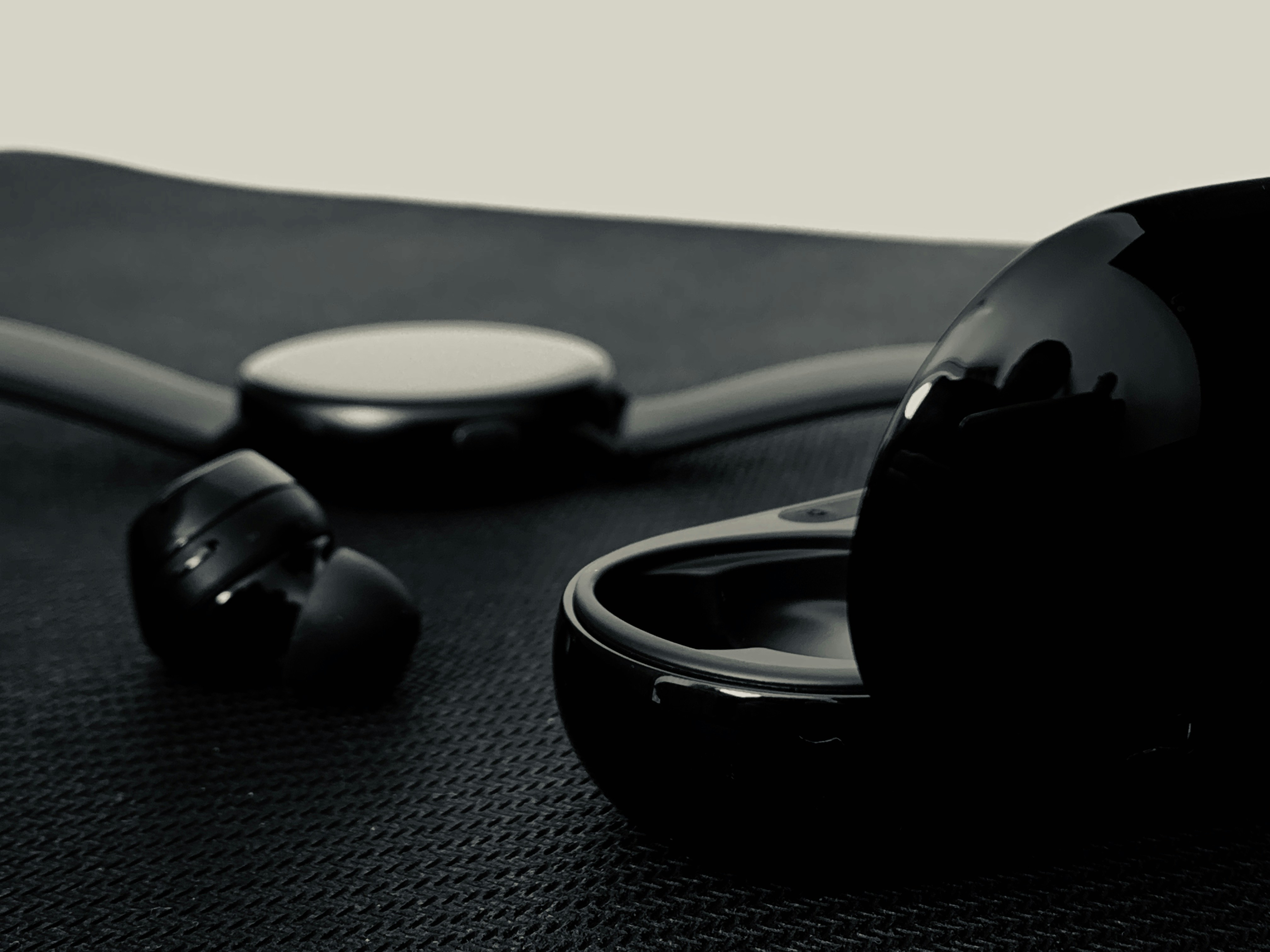 Wireless earbuds and smartwatch accessories displayed on dark minimal surface