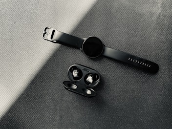 Trendy tech gadgets like wireless earbuds and smartwatches glowing softly on a sleek black surface.