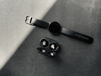 Trendy tech gadgets like wireless earbuds and smartwatches glowing softly on a sleek black surface.