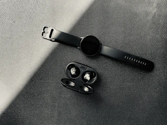 Modern wireless earbuds and smartwatches displayed on a dark, minimalist surface