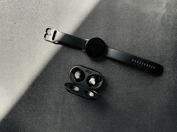 Modern wireless earbuds and smartwatches displayed on a dark, minimalist surface