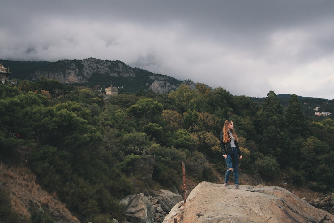 woman in blue denim jacket standing on brown rock during daytime