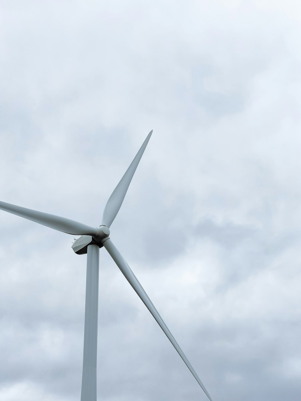 white wind turbine under white clouds during daytime