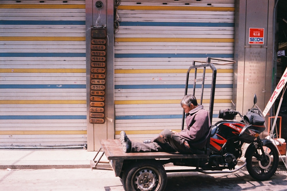 man in black jacket riding on black and red auto rickshaw