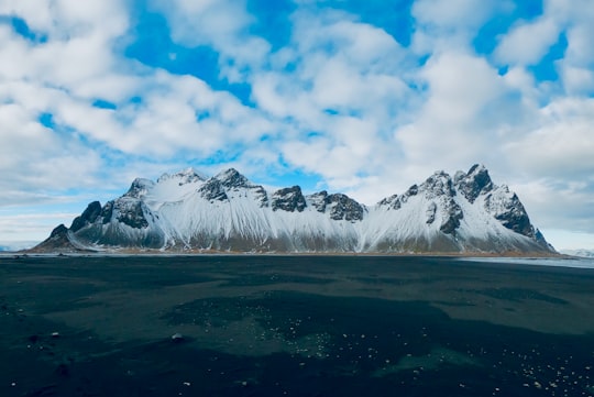 snow covered mountain under blue sky during daytime in Stokksnes Iceland