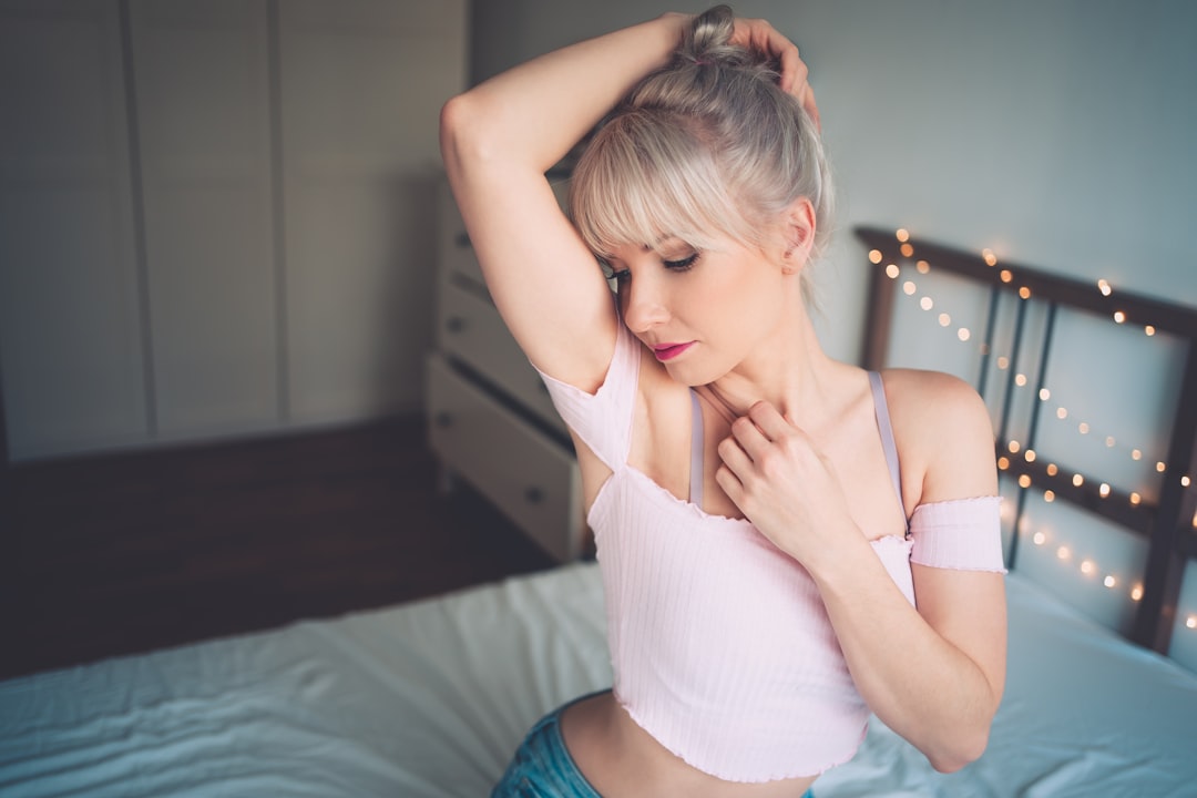 woman in white tank top and blue shorts sitting on bed