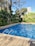 A pristine swimming pool surrounded by lush greenery under a clear blue sky.
