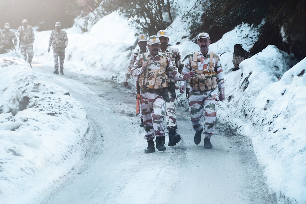 group of men in red and black uniform walking on snow covered road during daytime