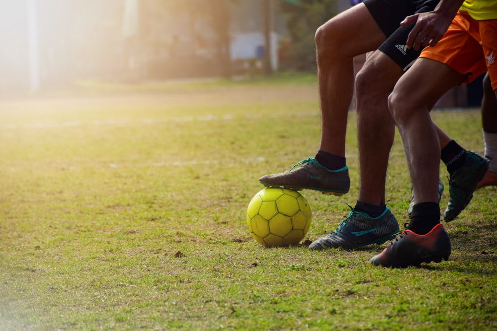 Homme en short noir et ballon de football Nike noir sur un terrain en herbe verte pendant la journée