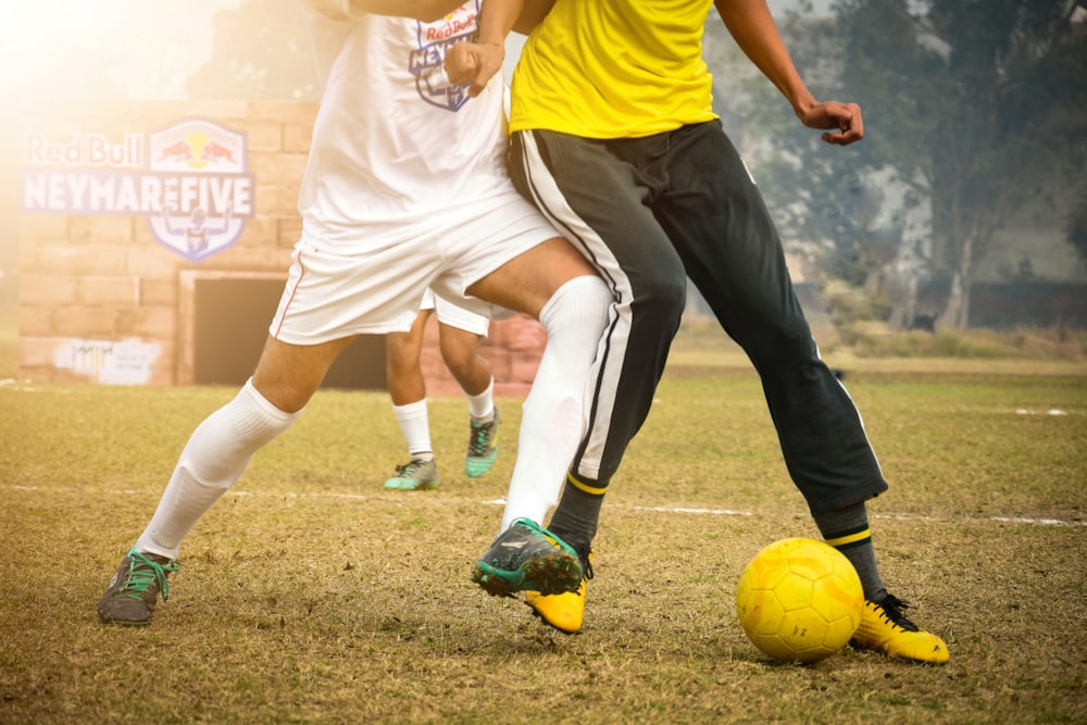 man in yellow shirt and black pants playing soccer