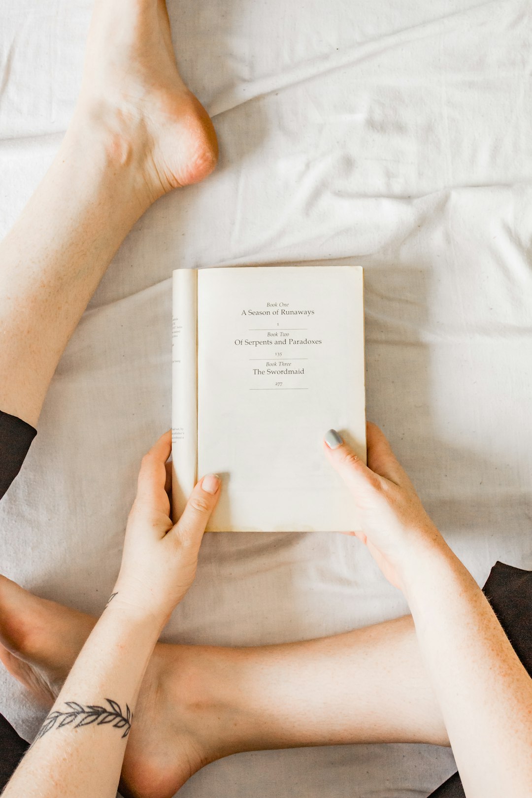 person holding white book on white textile