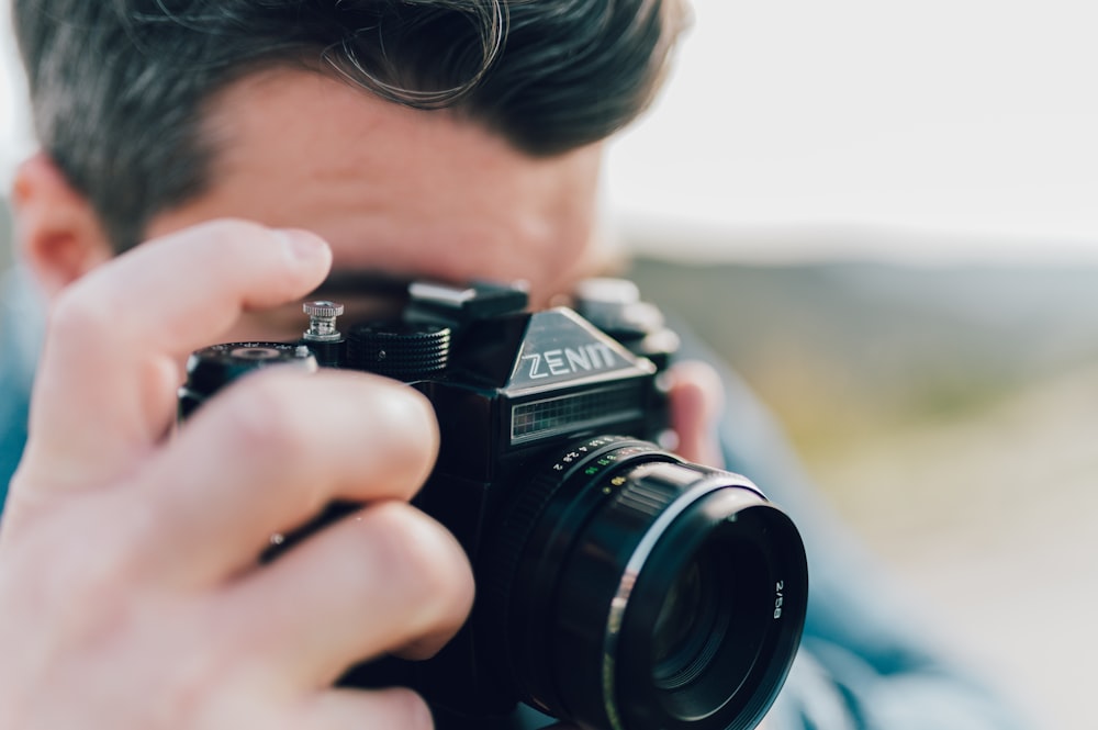 man holding black nikon dslr camera