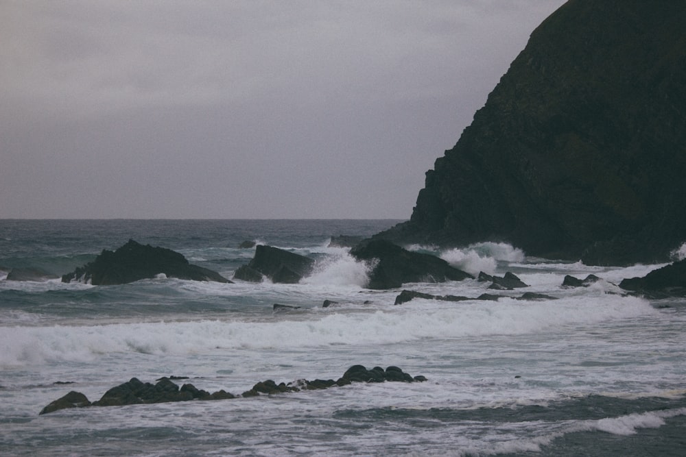 ocean waves crashing on black rock formation during daytime