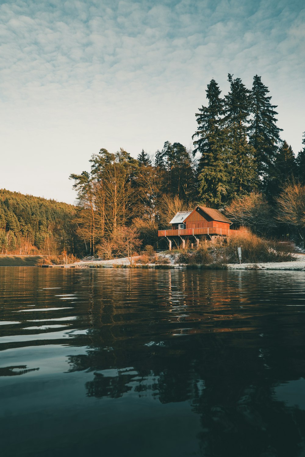 昼間は木々に囲まれた湖畔の茶色い木造家屋