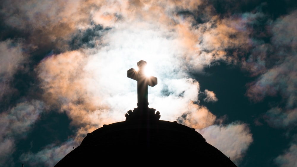 white cross on brown rock under white clouds