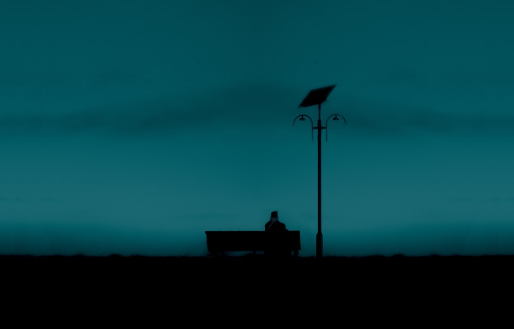 silhouette of person sitting on bench during night time