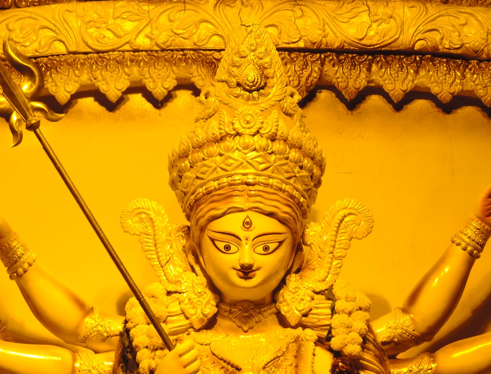 gold hindu deity figurine on brown wooden table