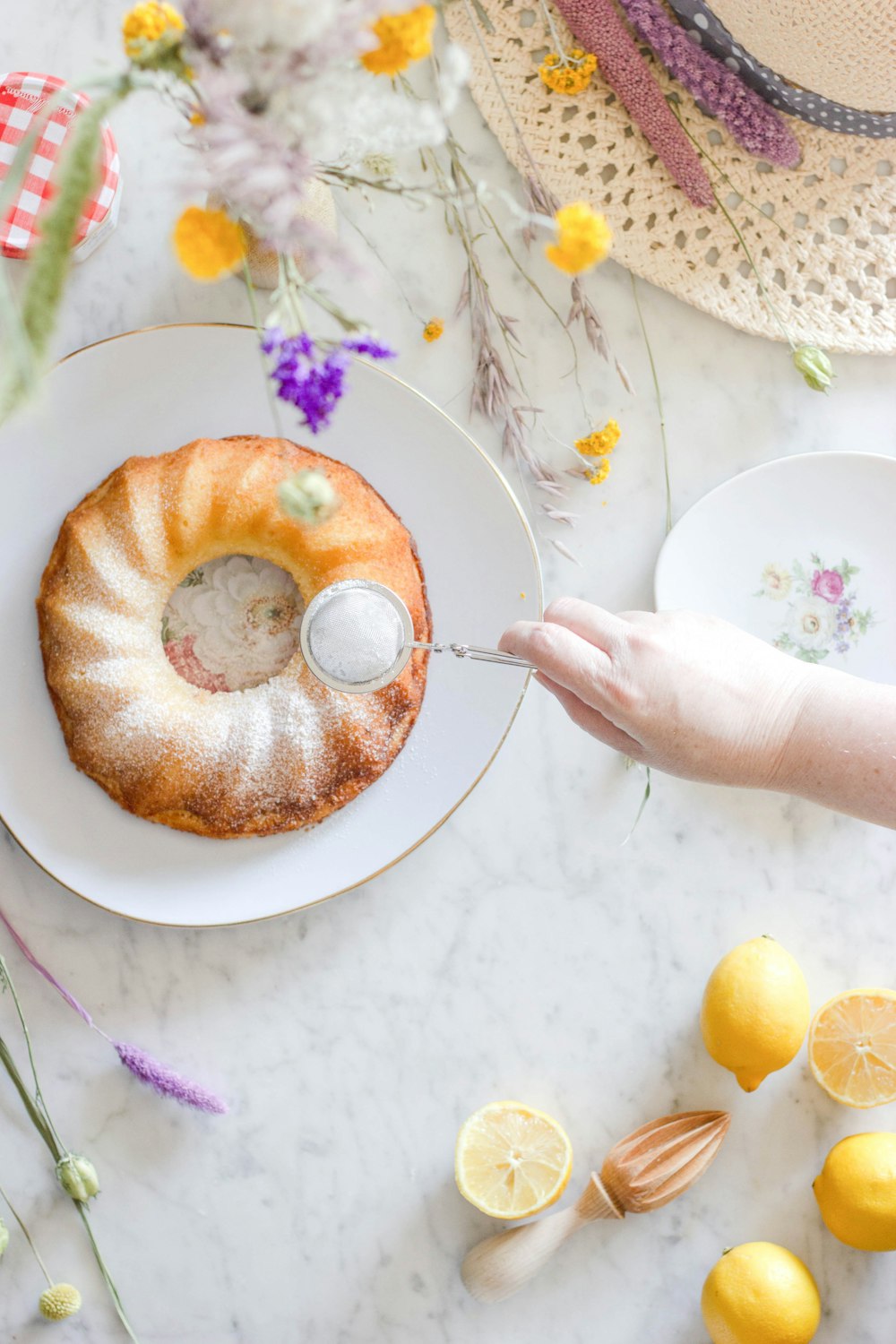 Persona sosteniendo una cuchara de acero inoxidable con rosquilla marrón en un plato de cerámica blanca