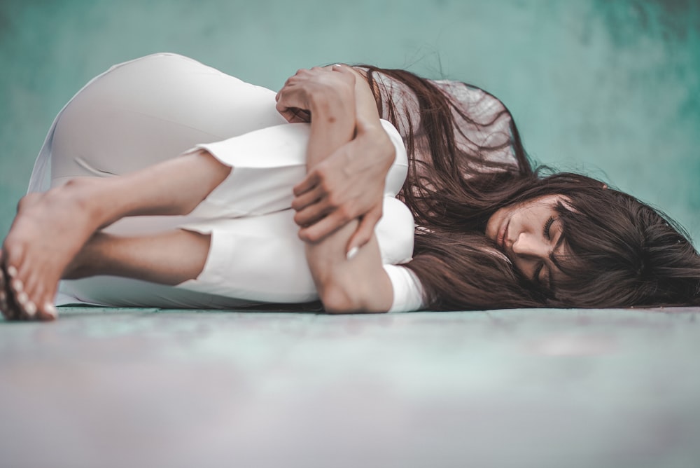 woman in white shirt lying on blue floor