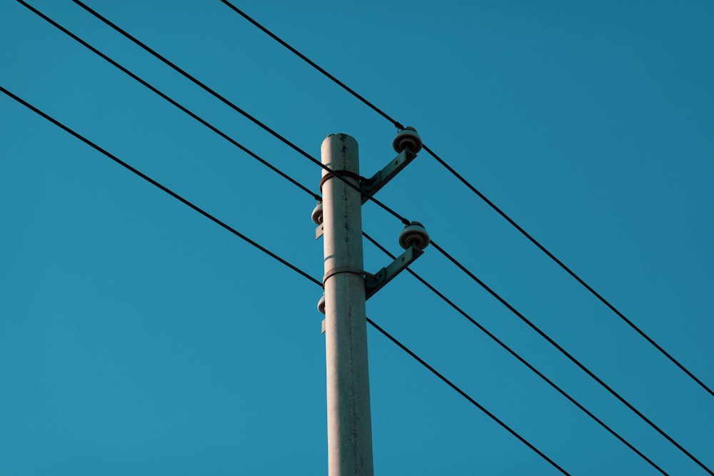 gray electric post under blue sky during daytime