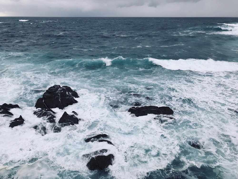 black rock formation on sea during daytime