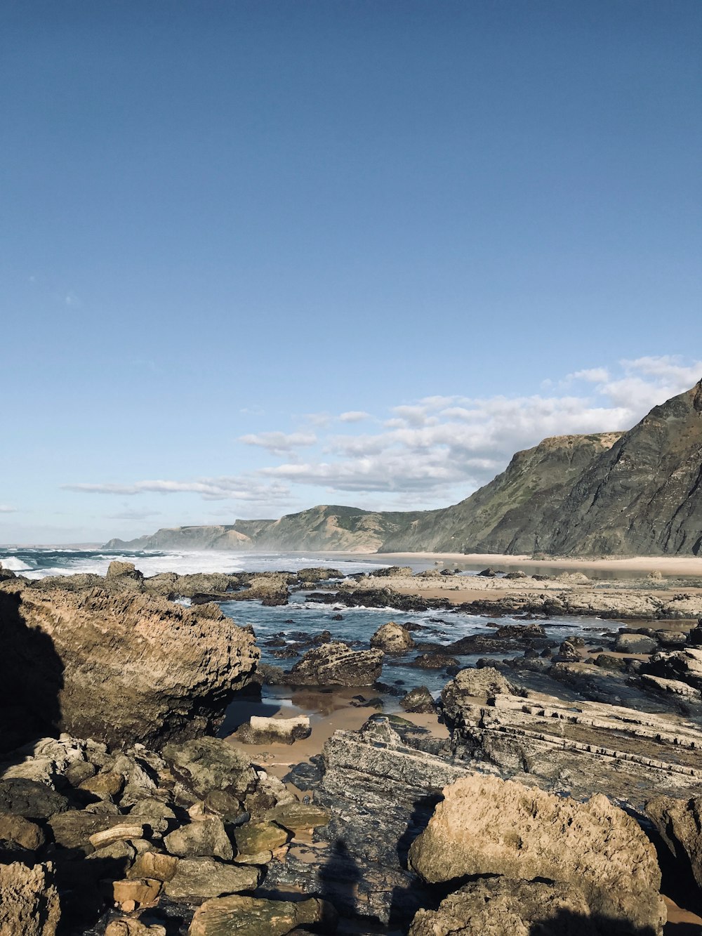 brown rocky shore near mountain under blue sky during daytime