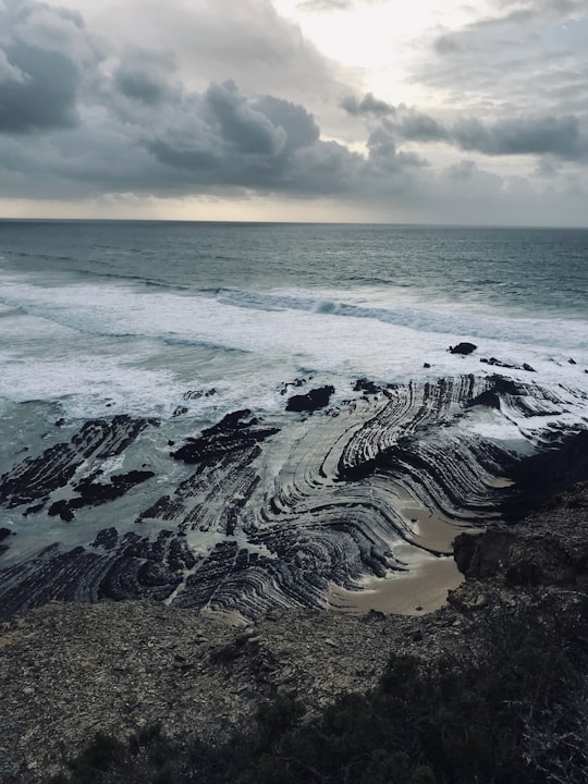 aerial view of ocean waves crashing on shore during daytime in Aljezur Portugal