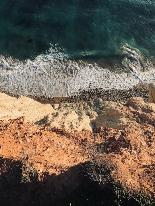 water waves hitting brown rocky shore during daytime in Lagos Portugal