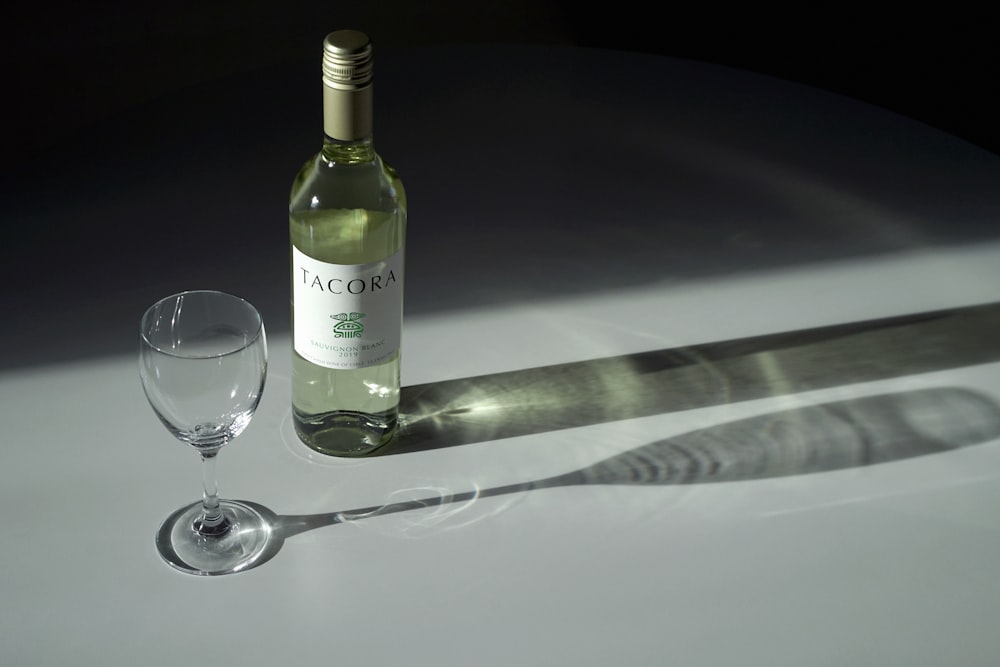 white labeled bottle beside wine glass on table
